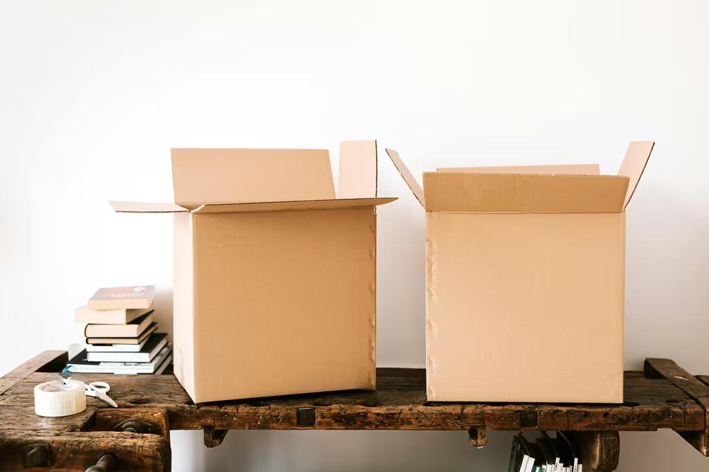 Photo of cardboard moving boxes and books on a table